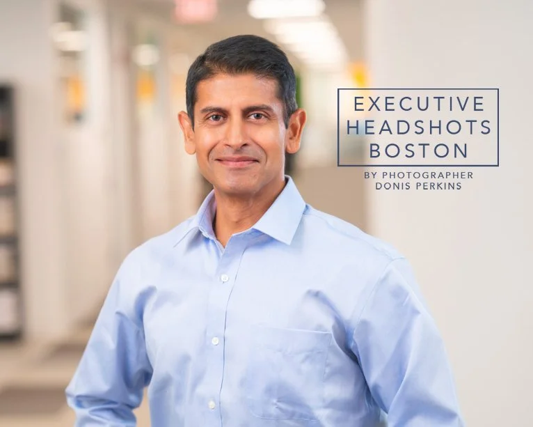 Man with short dark hair in a light blue dress shirt in a bright office corridor